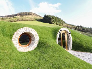 A hillside house with round window and arched door surrounded by grass at Nant y Garnedd Mallwyd near Dinas Mawddwy