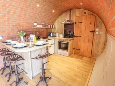 A kitchen with bar stools and a wooden door at Nant yr Esgair in Mallwyd near Dinas Mawddwy