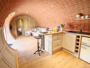 A kitchen and seating area with curved brick walls and wooden flooring at Nant yr Esgair in Mallwyd near Dinas Mawddwy