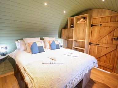 A bedroom with a double bed and wooden shelving unit with hangers at Nant yr Esgair Mallwyd near Dinas Mawddwy
