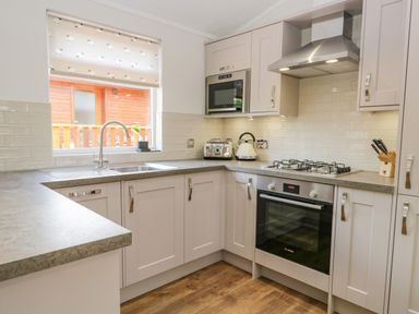 A kitchen with a sink microwave oven stovetop kettle toaster and a knife block at Kirkstone Lodge in Limefitt Park near Windermere