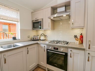 A kitchen with a stove oven microwave toaster kettle knife block and sink at Kirkstone Lodge in Limefitt Park near Windermere