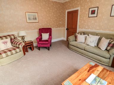 A living room with sofas an armchair a wooden door and a wooden coffee table at 19 Duke Street in Alnwick