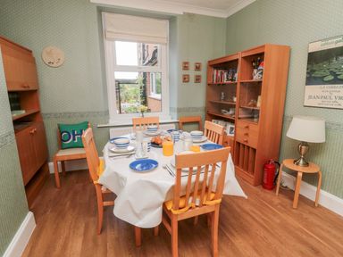A dining room with a table set for breakfast and wooden cabinets at 19 Duke Street in Alnwick