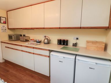 A kitchen counter with cabinets a microwave toaster kettle canisters and two white appliances at 19 Duke Street in Alnwick