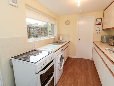 A kitchen with a stove washing machine sink cabinets and wooden floor at 19 Duke Street in Alnwick