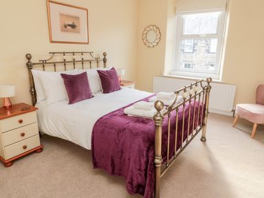 A bedroom with a metal bed frame and purple bedding at 19 Duke Street in Alnwick