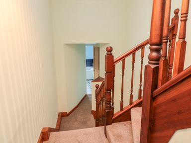 A carpeted staircase with wooden bannisters leading to a hallway and a partially visible bathroom at 19 Duke Street in Alnwick