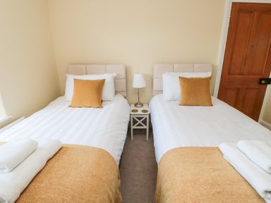 A bedroom with two single beds a small white bedside table and a lamp at 19 Duke Street in Alnwick