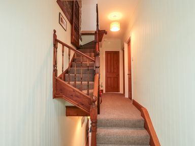 A carpeted staircase with wooden banisters and doors at the top in a hallway at 19 Duke Street in Alnwick