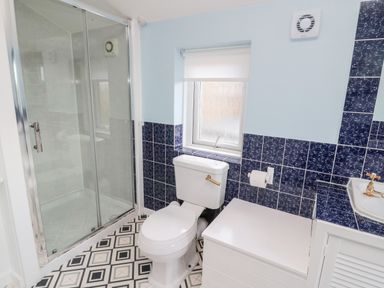 A bathroom with a shower enclosure a toilet a window and a sink at 19 Duke Street in Alnwick