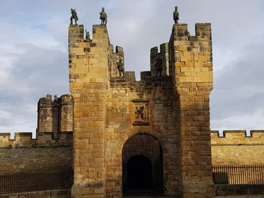 A stone castle gate with statues on top and a lion crest above the archway at 19 Duke Street in Alnwick