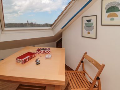 A wooden table and chair under a skylight window with game pieces on the table and framed artwork on the wall at 19 Duke Street Alnwick