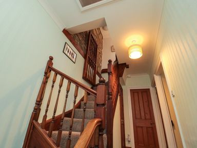 A wooden staircase with carpeted steps and a closed wooden door in a hallway at 19 Duke Street in Alnwick