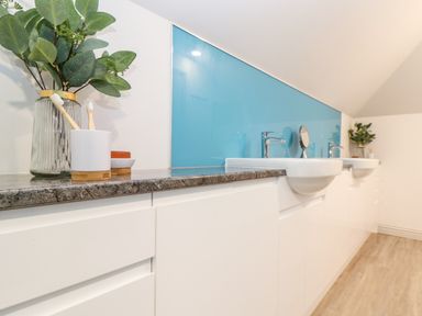 A bathroom countertop with two sinks and a blue backsplash with plants and toothbrushes at Penthouse 23 in Newquay