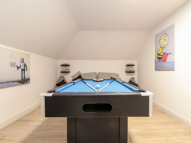 A game room with a blue pool table a gray sofa and wall art at Penthouse 23 in Newquay