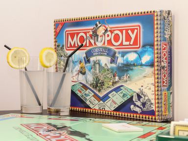 A Monopoly Cornwall Edition board game with two glasses of water with lemon slices and black straws