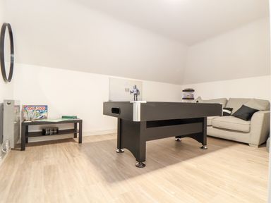 A game room with a black pool table a beige sofa a black table with board games and a round mirror on the wall at Penthouse 23 in Newquay
