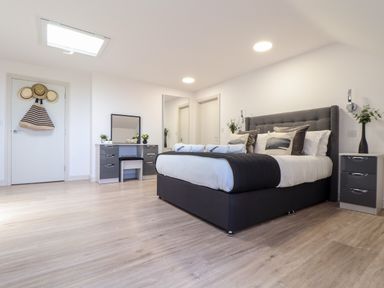 A bedroom with a large bed a dressing table mirror and a bedside cabinet at Penthouse 23 in Newquay