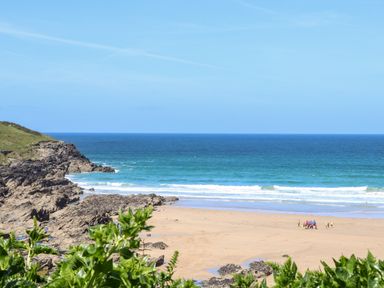 A beach with rocky cliffs and a group of people near the shoreline at Penthouse 23 in Newquay