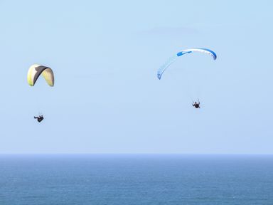 Two people paragliding over the ocean under a clear sky at Penthouse 23 in Newquay