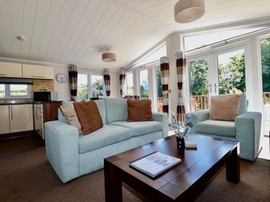 A living room with light blue sofas a wooden coffee table and large windows at 23 Bossiney Bay in Tintagel