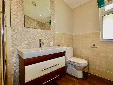 A bathroom with a sink vanity unit a toilet and a window at 23 Bossiney Bay in Tintagel