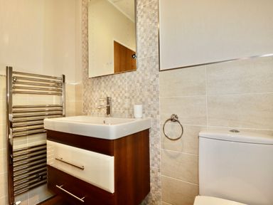 A bathroom with a sink cabinet mirror towel rack and toilet at 23 Bossiney Bay in Tintagel