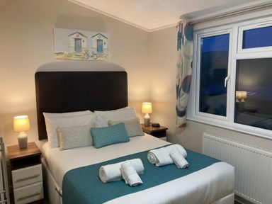 A bedroom with a bed towels bedside tables lamps and a window at 23 Bossiney Bay in Tintagel