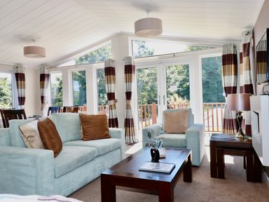 A living room with sofas a coffee table and large windows with striped curtains at 23 Bossiney Bay in Tintagel