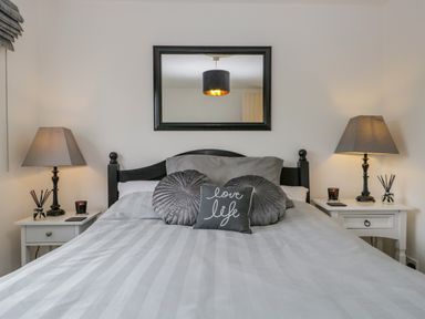 A bedroom with a bed with pillows a mirror above the bed and two lamps on bedside tables at Columbine Cottage in Hawkshead