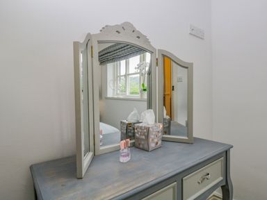 A vanity table with a three-panel mirror and tissue box in a room at Columbine Cottage in Hawkshead