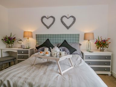 A bedroom with a bed that has a breakfast tray and two heart-shaped wall decorations at Columbine Cottage in Hawkshead