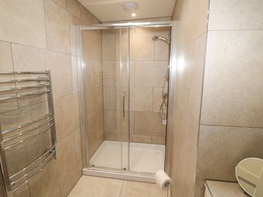 A bathroom with a glass shower enclosure a towel rack and a toilet paper holder at Forget Me Not Lodge in Bamburgh
