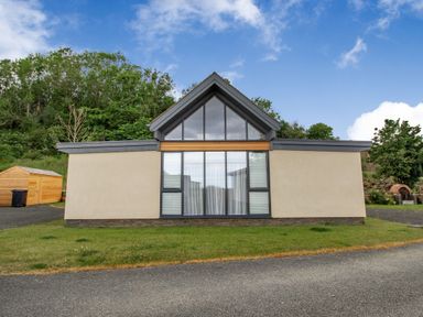 A modern single-story house with a large glass window and a triangular roof at Forget Me Not Lodge Bamburgh
