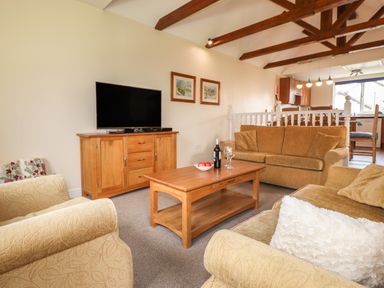 A living room with sofas a wooden coffee table and a TV cabinet at Tilly Mint Cottage Nr Ullswater
