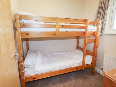 A bedroom with wooden bunk beds and white bedding at Tilly Mint Cottage Nr Ullswater