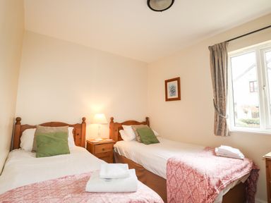 A bedroom with two single beds a bedside table with a lamp and a window at Tilly Mint Cottage Nr Ullswater