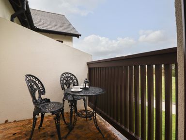 A small balcony with two metal chairs a round table and cups at Tilly Mint Cottage Nr Ullswater