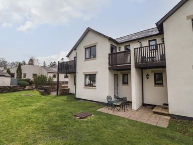 An exterior view of a white two story house with balconies and a small patio set on a lawn at Tilly Mint Cottage Nr Ullswater