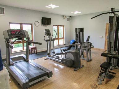 A gym room with treadmill elliptical machine weight machines and a blue exercise ball at Tilly Mint Cottage Nr Ullswater