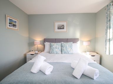 A bedroom with a bed cushions lamps and rolled towels at Chesil Retreat in Weymouth