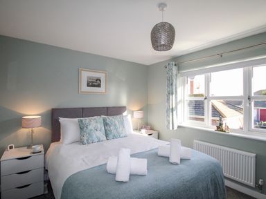 A bedroom with a double bed bedside tables lamps and a window at Chesil Retreat in Weymouth