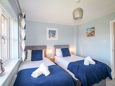 A bedroom with two single beds blue blankets and white towels at Chesil Retreat in Weymouth