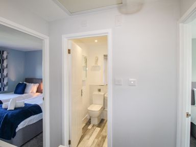 A hallway with doors leading to a bathroom and two bedrooms at Chesil Retreat in Weymouth