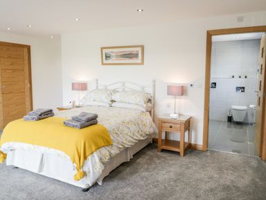 A bedroom with a double bed two bedside tables with lamps and an en suite bathroom at The Annexe in Llanfairpwllgwyngyll