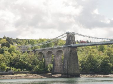A stone suspension bridge over a river with trees in the background at The Annexe in Llanfairpwllgwyngyll