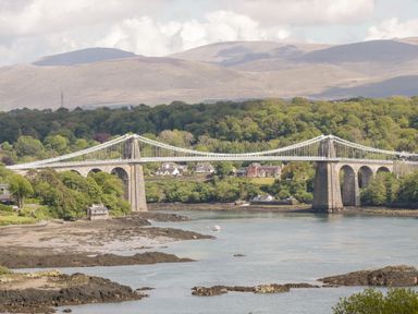 A suspension bridge over a river with hills and trees in the background at The Annexe in Llanfairpwllgwyngyll