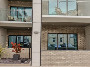 The exterior of a modern building with balconies and glass railings and red-leaved plant at 30 Cliff Edge in Newquay