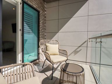 A balcony with two wicker chairs and a small round wicker table at 30 Cliff Edge in Newquay
